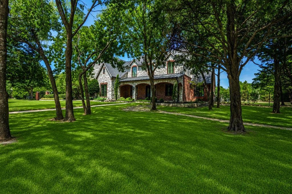 424 Wyndemere Boulevard, Heath, TX 75032 Stone and brick exterior with arched entryway, dormer windows, and a black shingle roof
