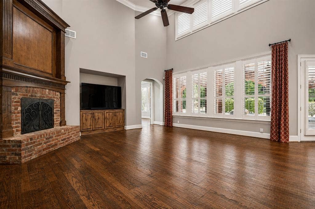 424 Wyndemere Boulevard, Heath, TX 75032 Two-story ceiling, wood-finish flooring, brick fireplace with wood mantel, built-in media cabinet, and plantation shutters