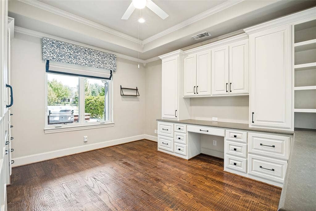 424 Wyndemere Boulevard, Heath, TX 75032 Bright home office featuring extensive white cabinetry with brushed metal hardware, a spacious work surface with multiple storage drawers, and wood-finish flooring