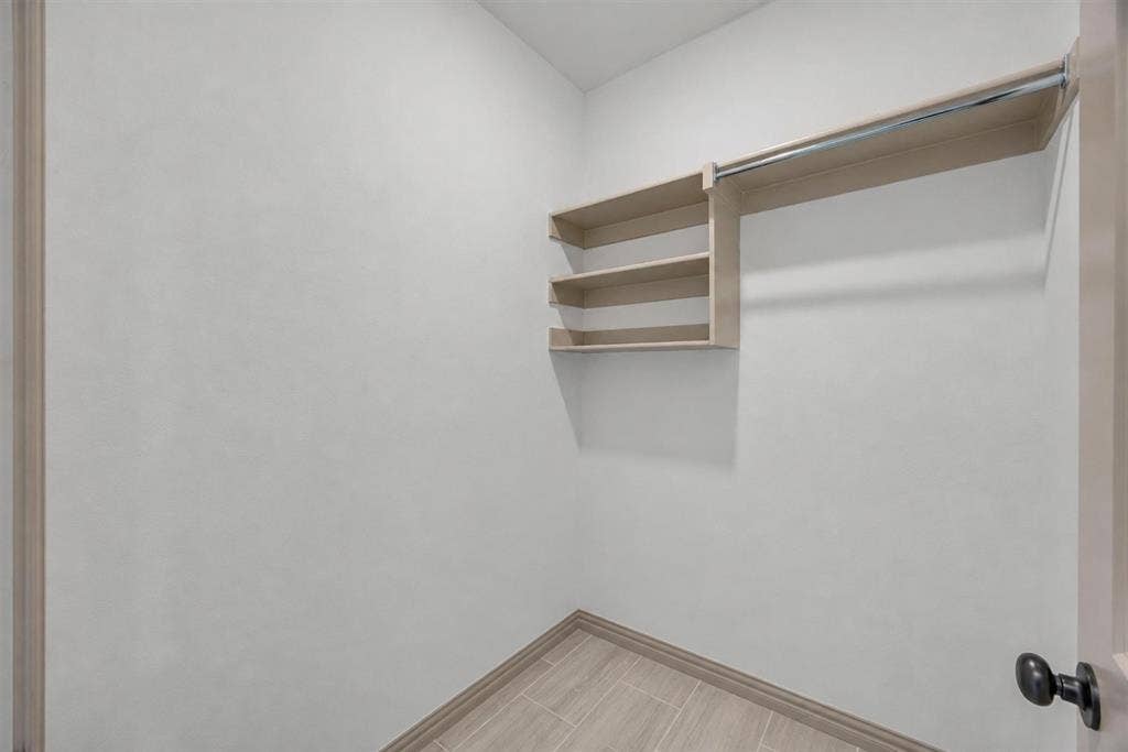 Built-in shelving with hanging rod, tile flooring, and neutral wall tones