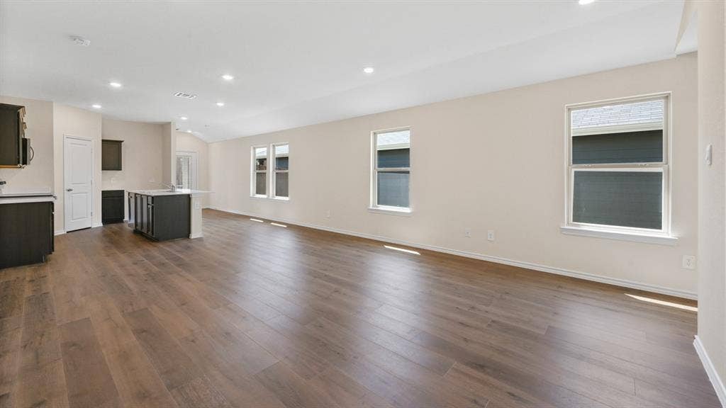 Open-concept living space featuring wood-finish flooring, recessed lighting, and multiple windows