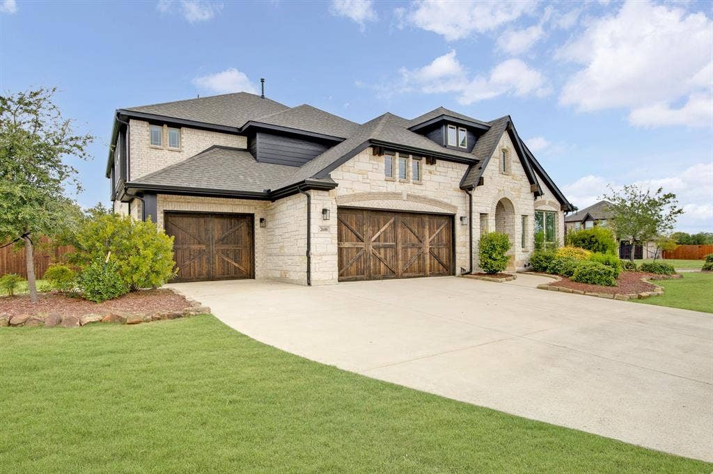 2600 Gavin Drive, Mansfield, TX 76063 Striking two-car garage with wood-finish doors anchors this elegant stone and brick exterior, complemented by a circular driveway and manicured lawn