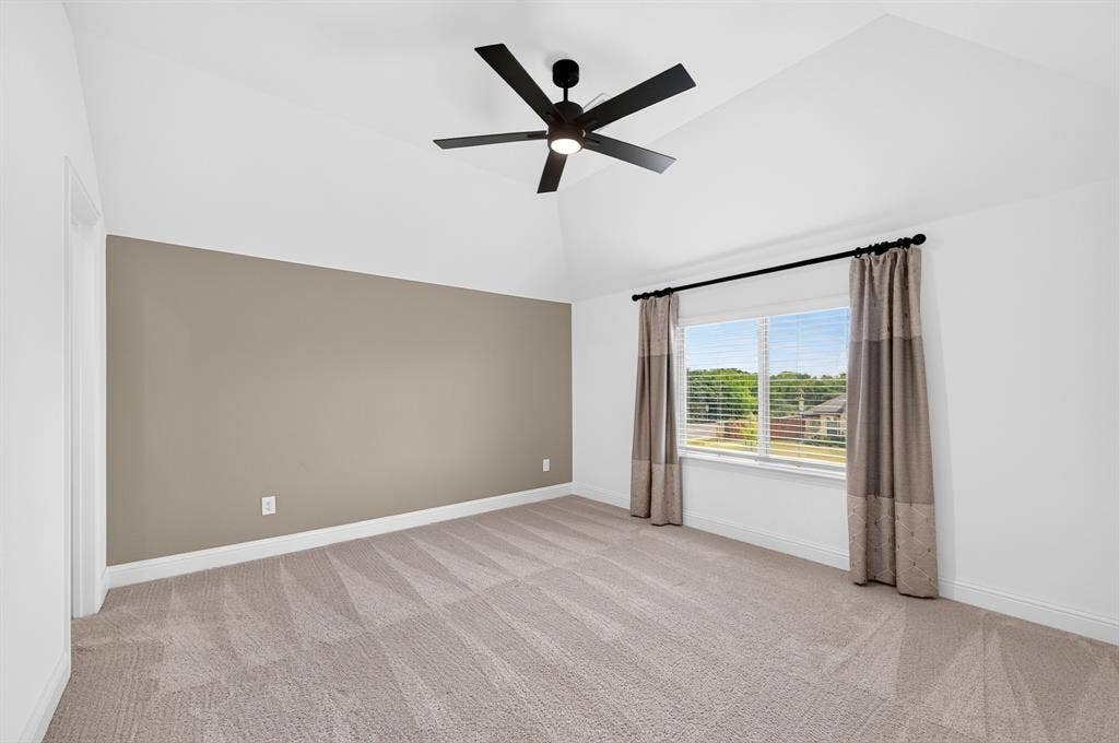 2600 Gavin Drive, Mansfield, TX 76063 Bedroom #4 with ensuite bathroom featuring neutral taupe accent wall, wood-finish flooring with linear plank pattern, ceiling fan with dark finish, and large window with natural light and exterior views framed by neutral drapery