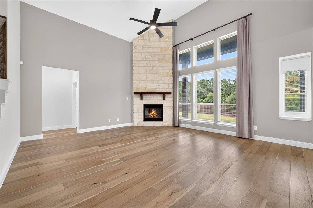 2600 Gavin Drive, Mansfield, TX 76063 Spacious living area showcasing hardwood flooring, soaring ceilings with ceiling fan, and abundant natural light from multi-pane glass doors and windows