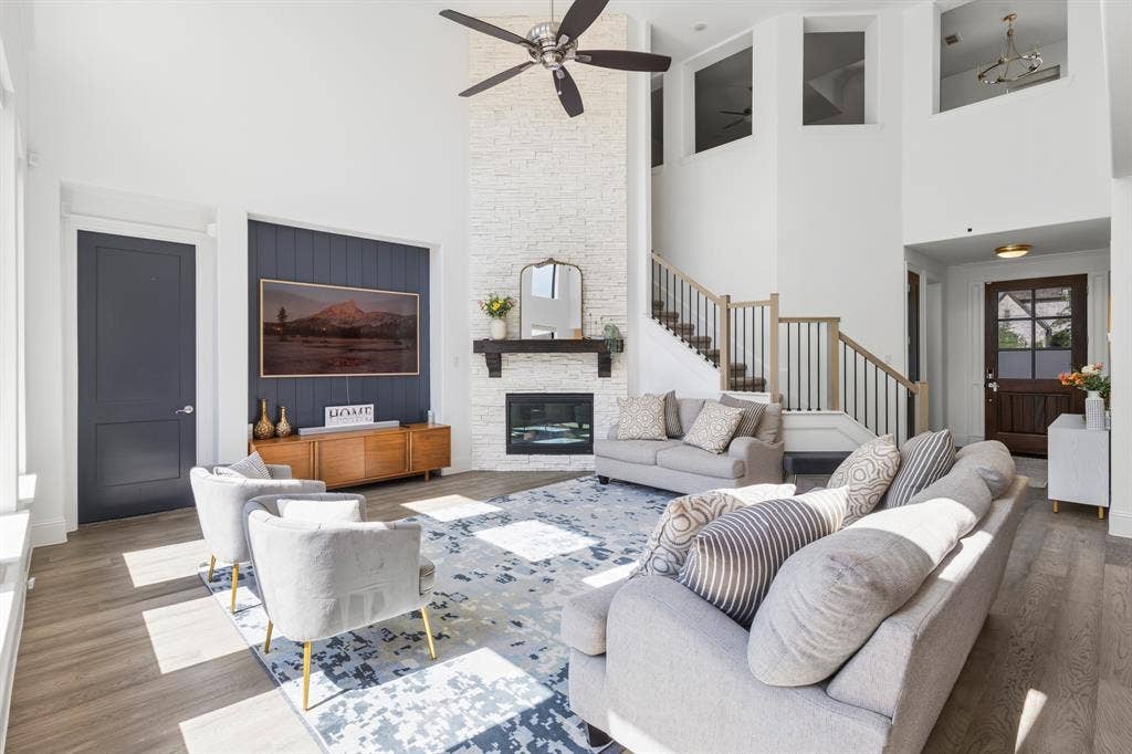Two-story interior with a stone-finish fireplace, built-in electric fireplace, recessed ceiling fan, and wood-finish flooring
