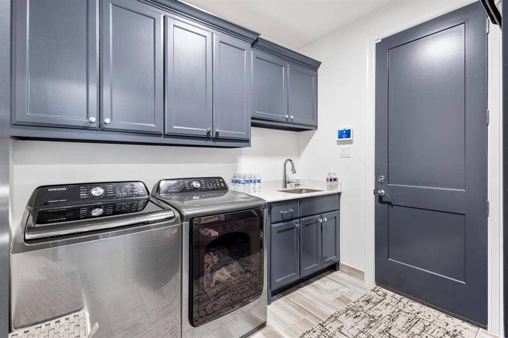 Laundry room featuring extensive cabinetry, a built-in sink with a gooseneck faucet, light-toned countertop space, and wood-finish flooring