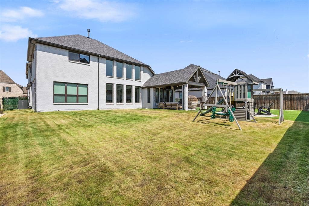 Expansive backyard featuring a manicured lawn, a covered outdoor living area, and a privacy fence