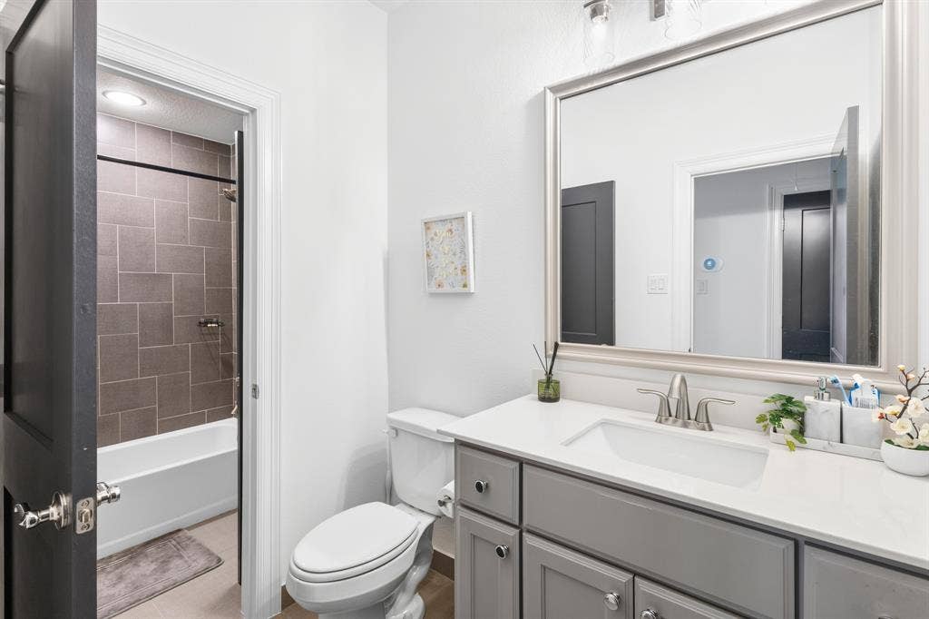 Vanity with a white countertop and undermount sink, framed mirror, and tile-surround bathtub