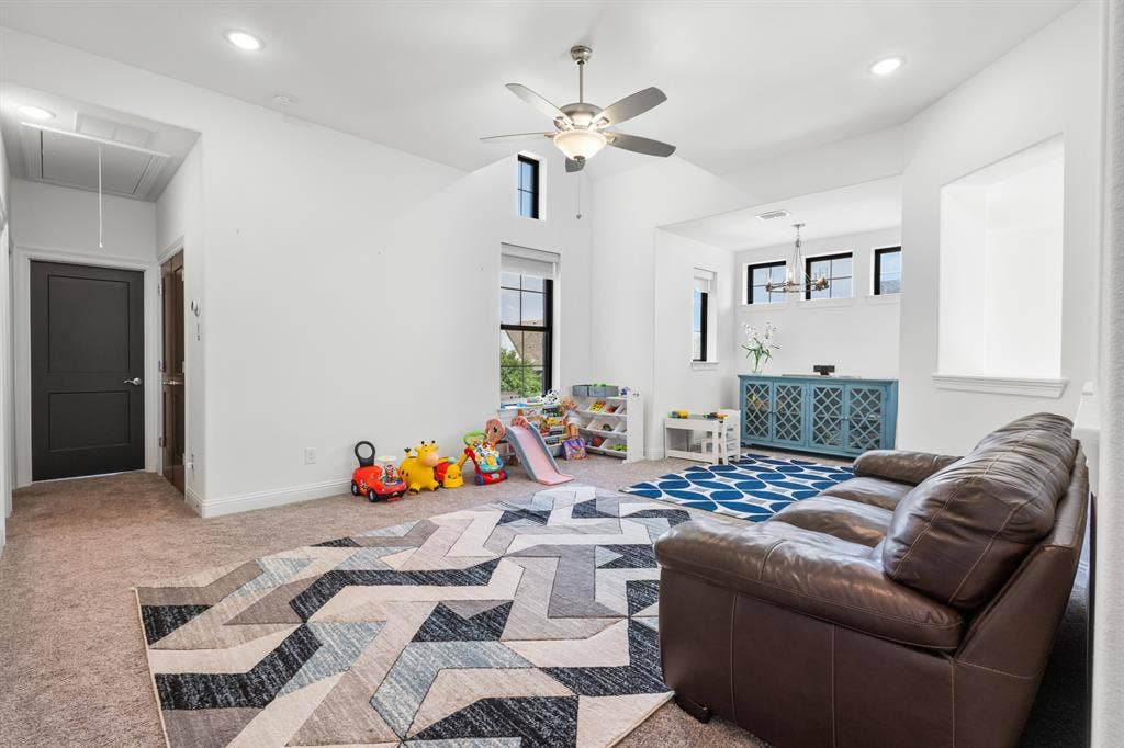 Spacious room featuring vaulted ceilings, recessed lighting, ceiling fan, and carpeted flooring
