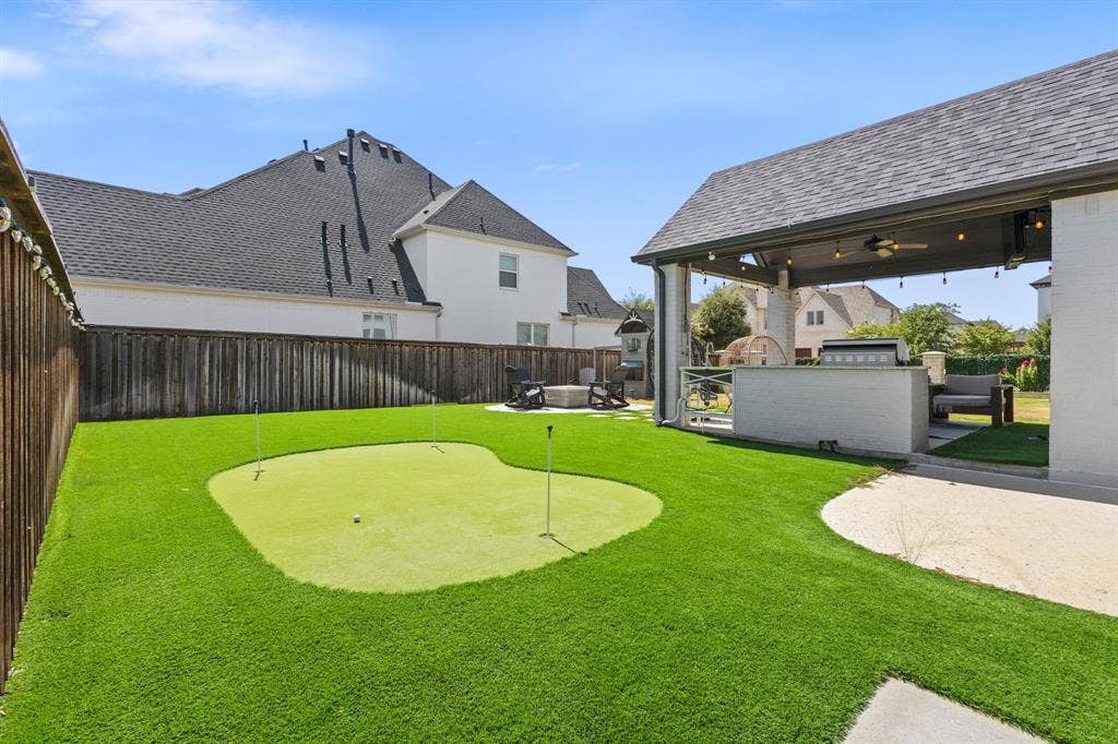 Covered patio with integrated outdoor kitchen, artificial turf, and a putting green