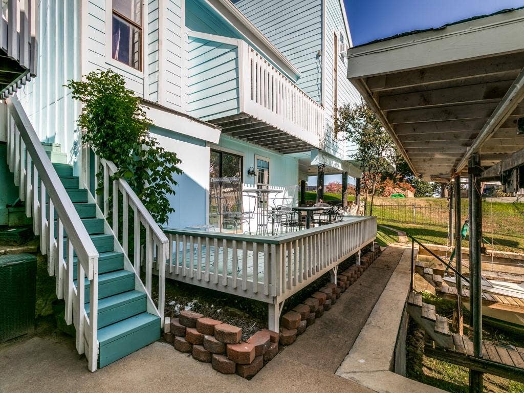 Multi-level exterior with light blue siding, a ground-level deck with white railings, and a covered boat dock