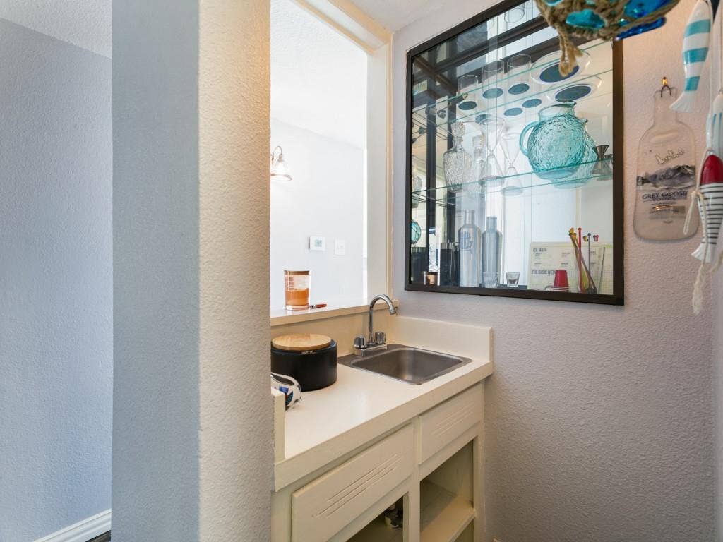 Built-in wet bar featuring a stainless steel sink, under-counter storage, and an illuminated display cabinet