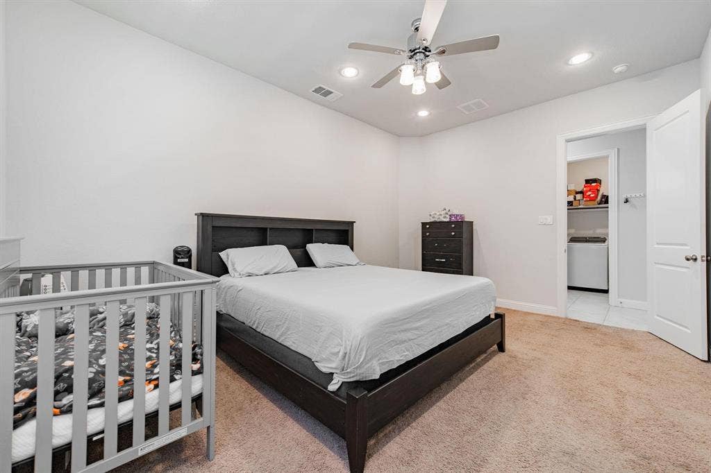 Spacious primary bedroom with dark wood platform bed frame, neutral wall finishes, and carpeted flooring