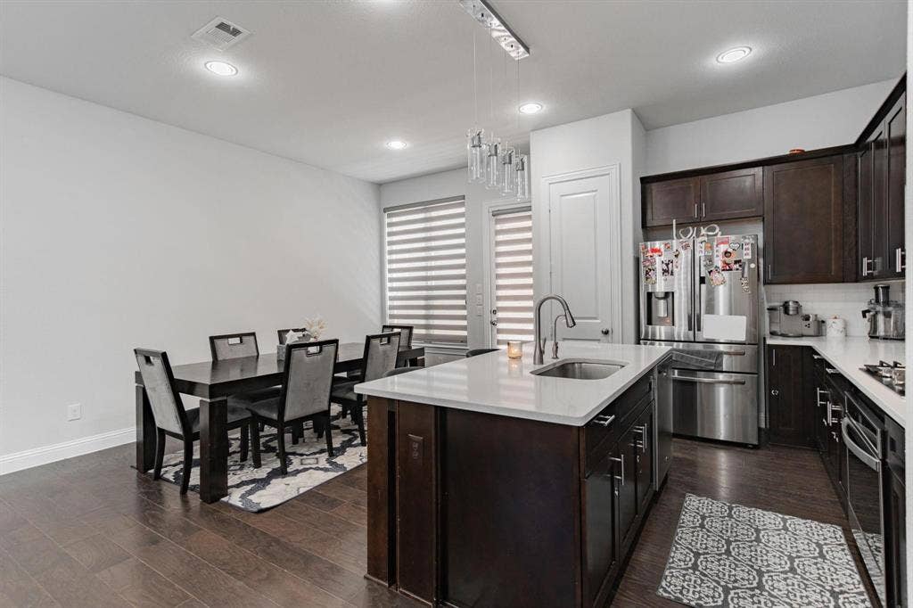 Kitchen with dark wood-finish flooring, recessed lighting, and a kitchen island with a single-basin sink