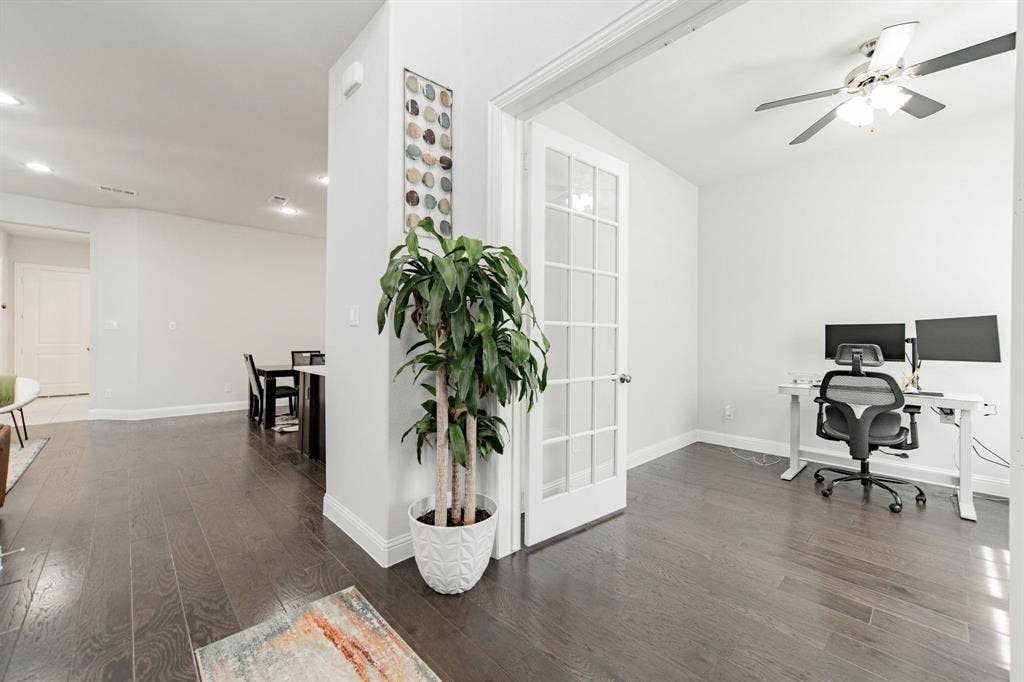 Dark wood-finish flooring throughout, French doors with glass panels, recessed lighting, and ceiling fan with light fixture