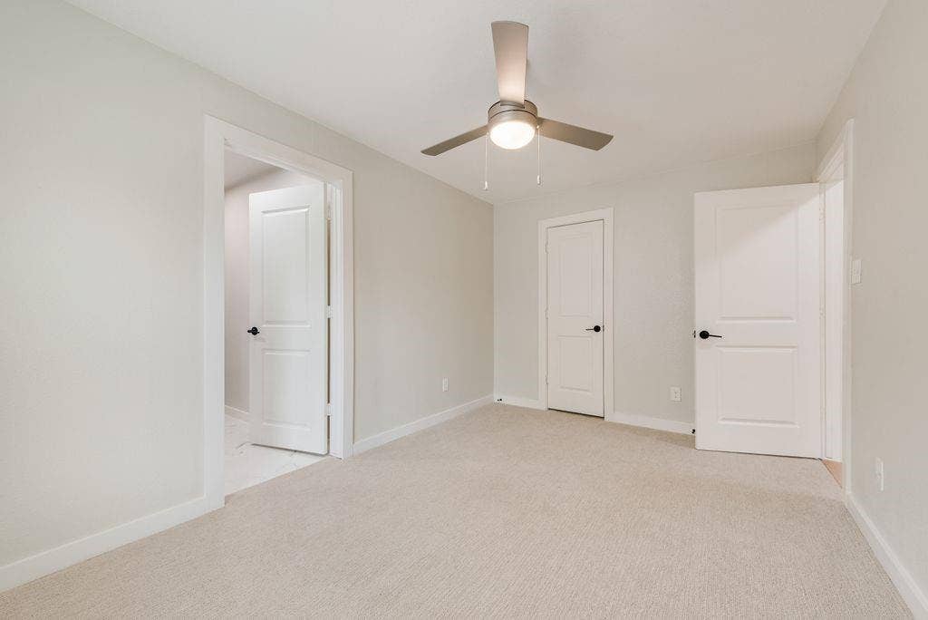 307 N 4th Street, Crandall, TX 75114 Neutral-toned carpeting, modern ceiling fan, white interior doors, and crisp white trim