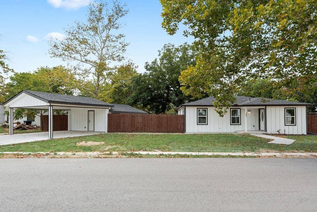 307 N 4th Street, Crandall, TX 75114 White vertical siding exterior with black trim windows, a covered front entry, and a dedicated carport