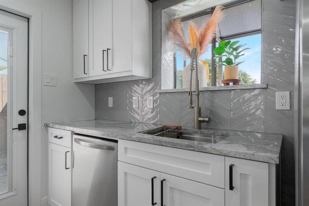 1805 W Spring Creek Parkway, #MM2, Plano, TX 75023 Modern kitchen featuring white shaker-style cabinetry, stainless steel appliances including a dishwasher, gray tile backsplash with geometric pattern detailing, quartz countertops, and a professional-grade pull-down faucet