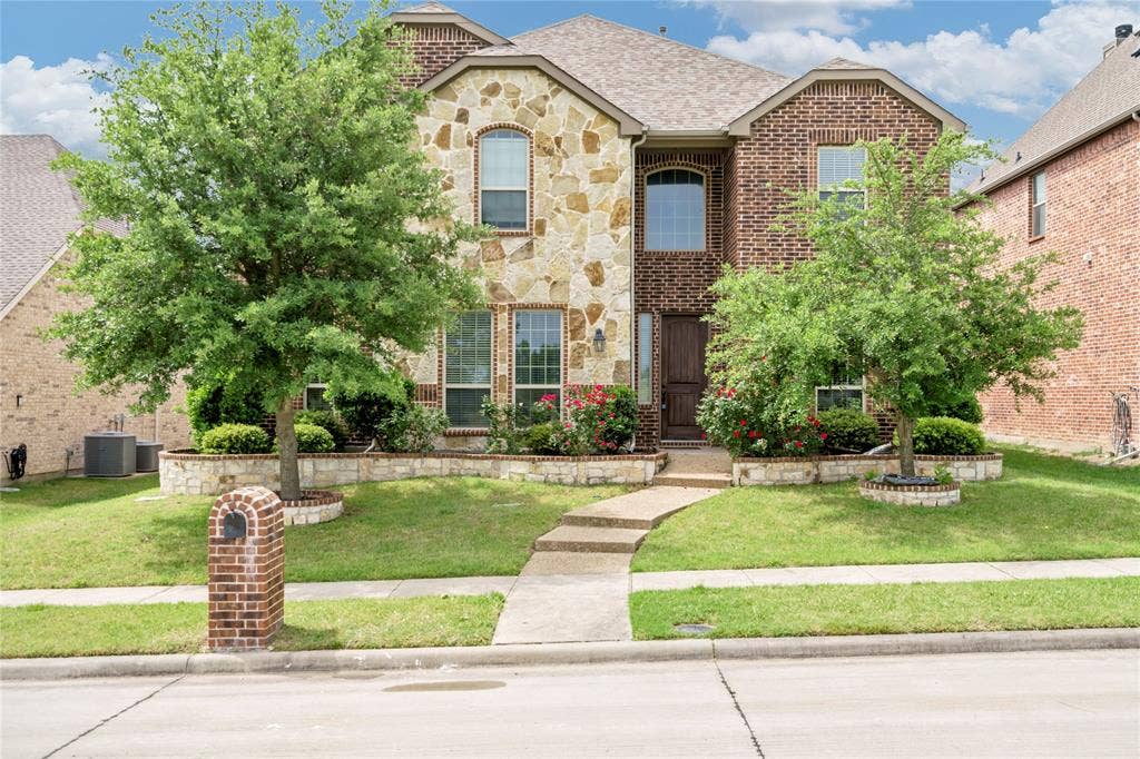 Brick and stone exterior with arched windows, a multi-level roofline, and established landscaping