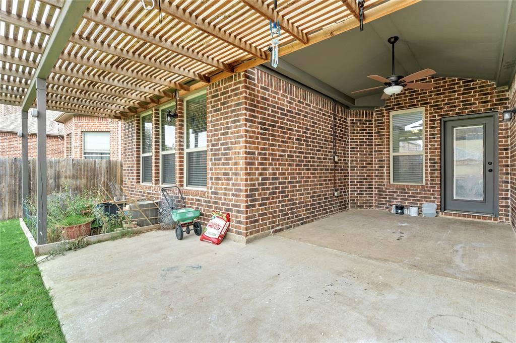 Covered patio featuring a ceiling fan, brick exterior, and wood lattice pergola