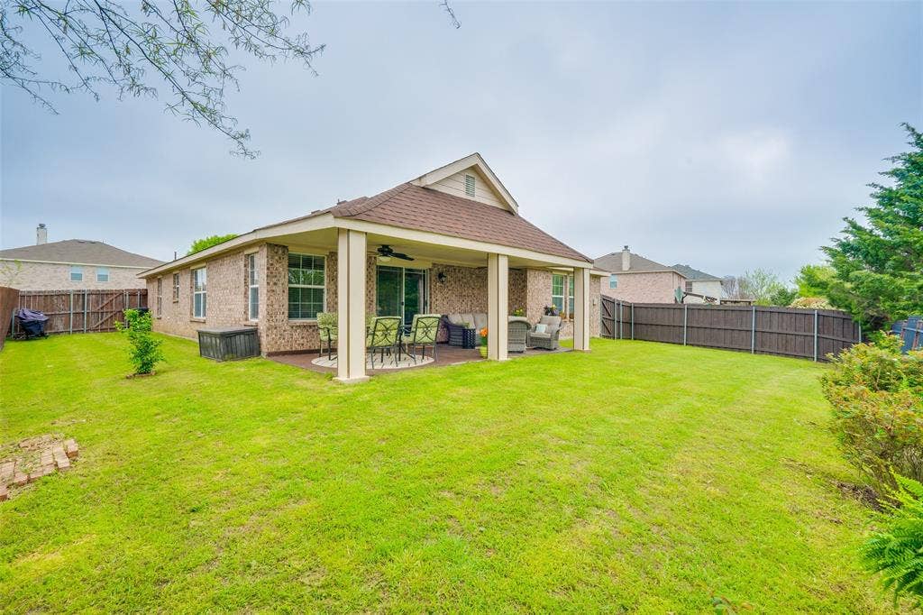 2035 Matagorda Lane, Grand Prairie, TX 75052 Expansive green lawn, covered patio with column supports, brick exterior, and full privacy fencing