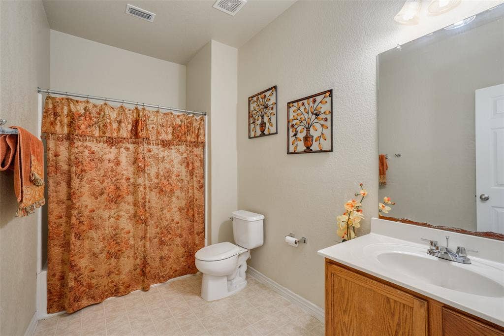 2035 Matagorda Lane, Grand Prairie, TX 75052 Bathroom with a white vanity sink, wood-finish cabinetry, and an integrated bathtub