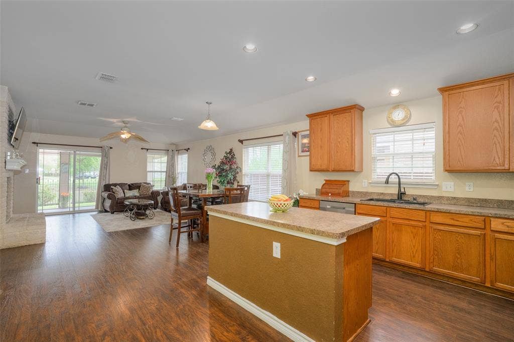 2035 Matagorda Lane, Grand Prairie, TX 75052 Expansive wood-finish flooring throughout, kitchen island with counter seating, stainless steel appliances, and a brick fireplace