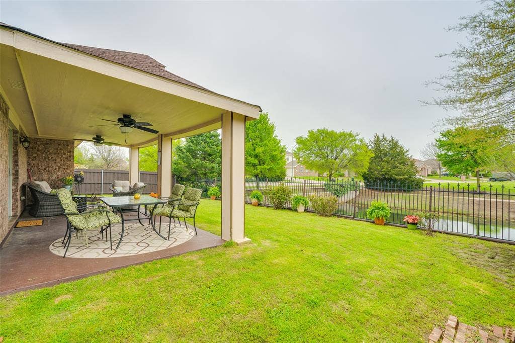 2035 Matagorda Lane, Grand Prairie, TX 75052 Expansive covered patio with dual ceiling fans, brick exterior detailing, and a manicured lawn