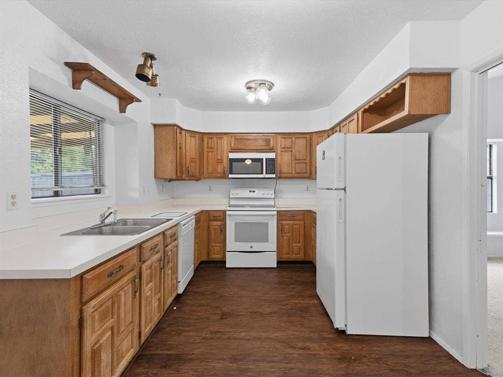 7612 Jerome Drive, Plano, TX 75025 Kitchen featuring wood-finish cabinetry, white countertops, stainless steel sink, and white appliances