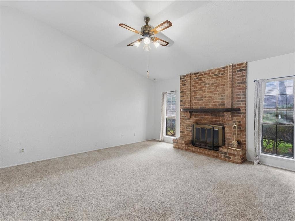 7612 Jerome Drive, Plano, TX 75025 Vaulted ceilings with a ceiling fan, brick fireplace with a wood mantle, and multiple windows allowing natural illumination