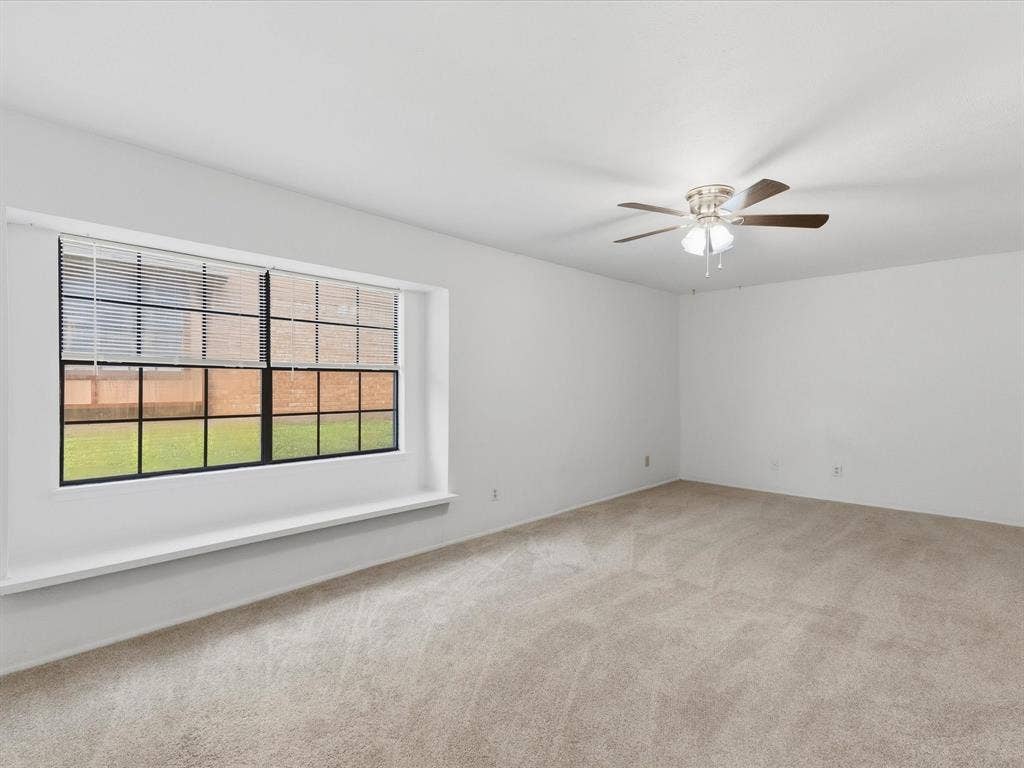 7612 Jerome Drive, Plano, TX 75025 Expansive room featuring neutral-toned carpeting, a ceiling fan with light fixture, and a large window with horizontal blinds and a window ledge