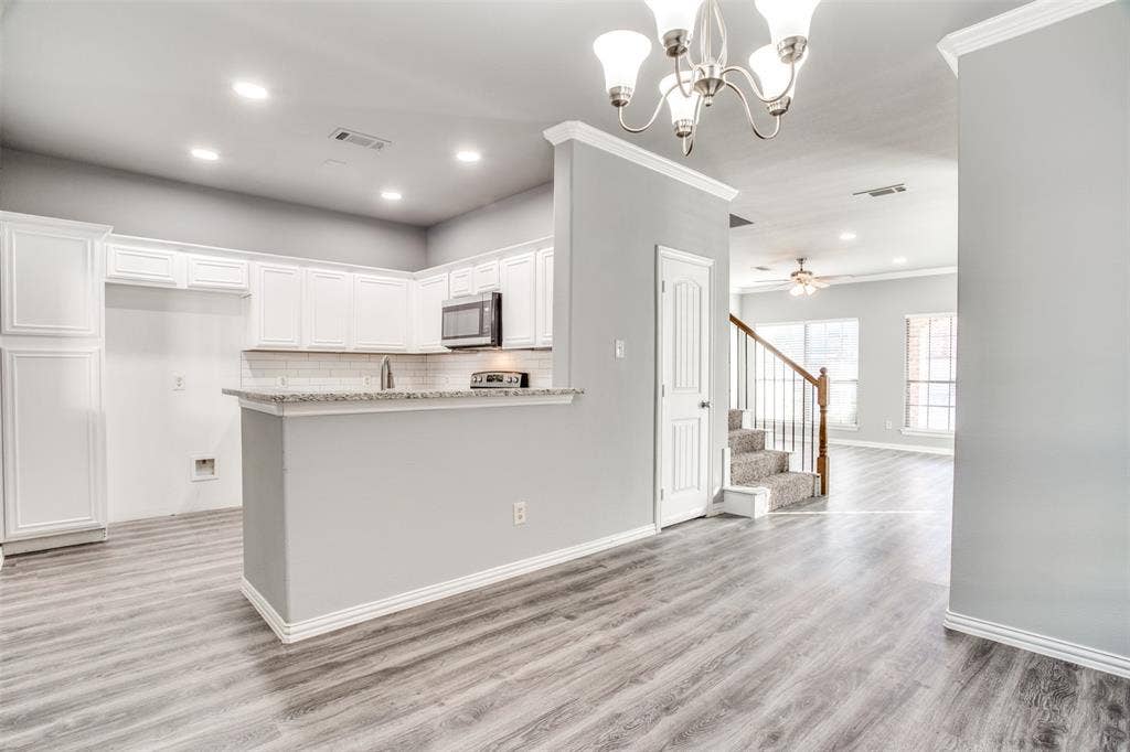 2364 Calendar Court, Grand Prairie, TX 75050 Kitchen featuring white shaker cabinetry, stainless steel microwave, light-toned wood-finish flooring, recessed lighting, and a breakfast bar with a speckled countertop