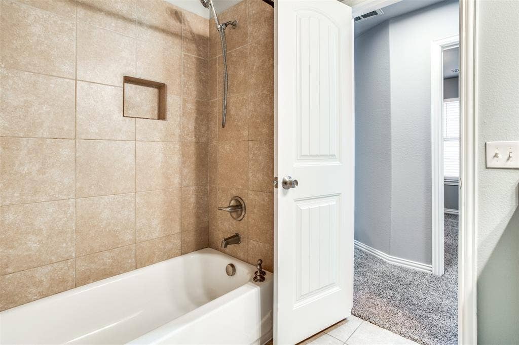 2364 Calendar Court, Grand Prairie, TX 75050 Bathtub with tiled surround, integrated shower niche, and brushed nickel fixtures
