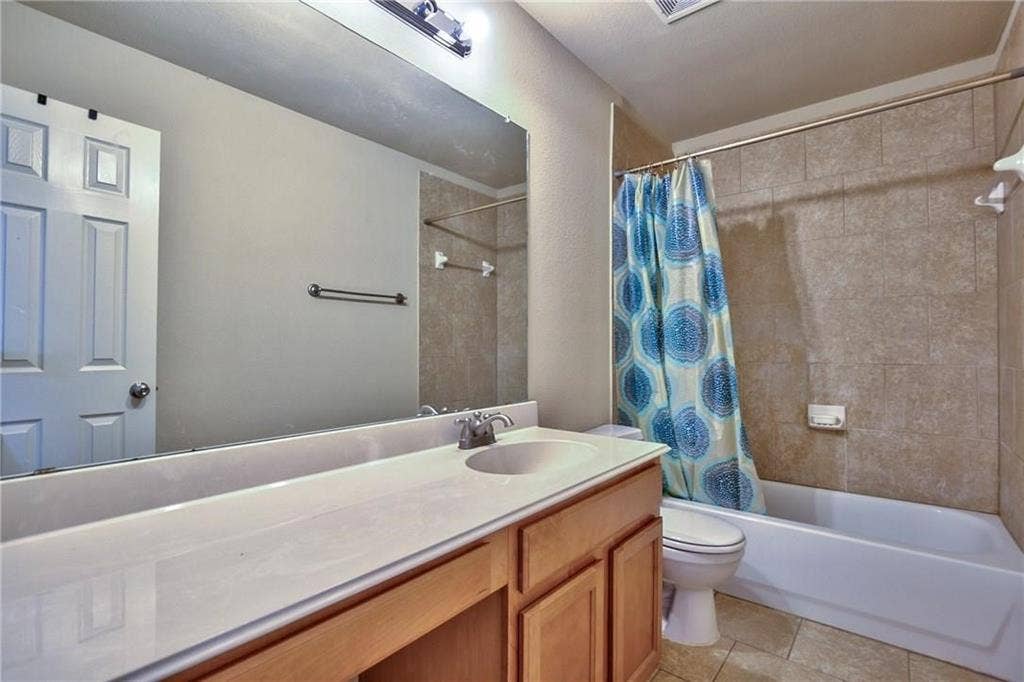 7108 Jessup Court, Plano, TX 75074 Bathroom featuring a white vanity with integrated sink, light wood-finish cabinetry, a large wall mirror, and a tiled shower/tub combination