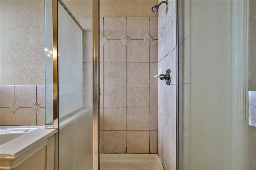 7108 Jessup Court, Plano, TX 75074 Tiled shower enclosure featuring a dark bronze shower head and coordinating fixtures