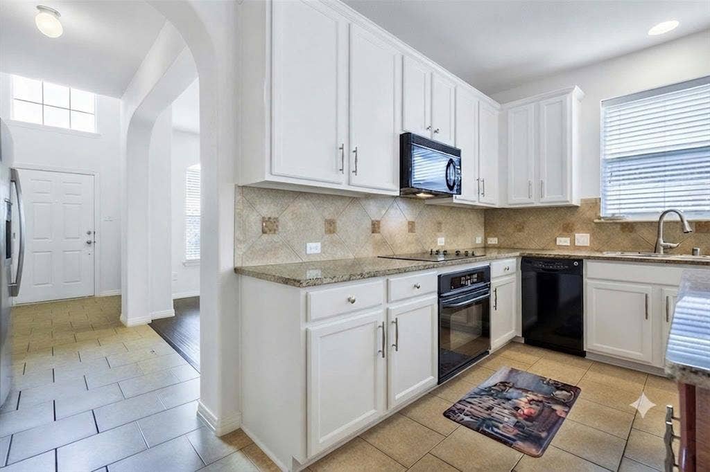 7108 Jessup Court, Plano, TX 75074 Kitchen featuring white cabinetry, granite countertops, tile backsplash, stainless steel sink with gooseneck faucet, and integrated black appliances