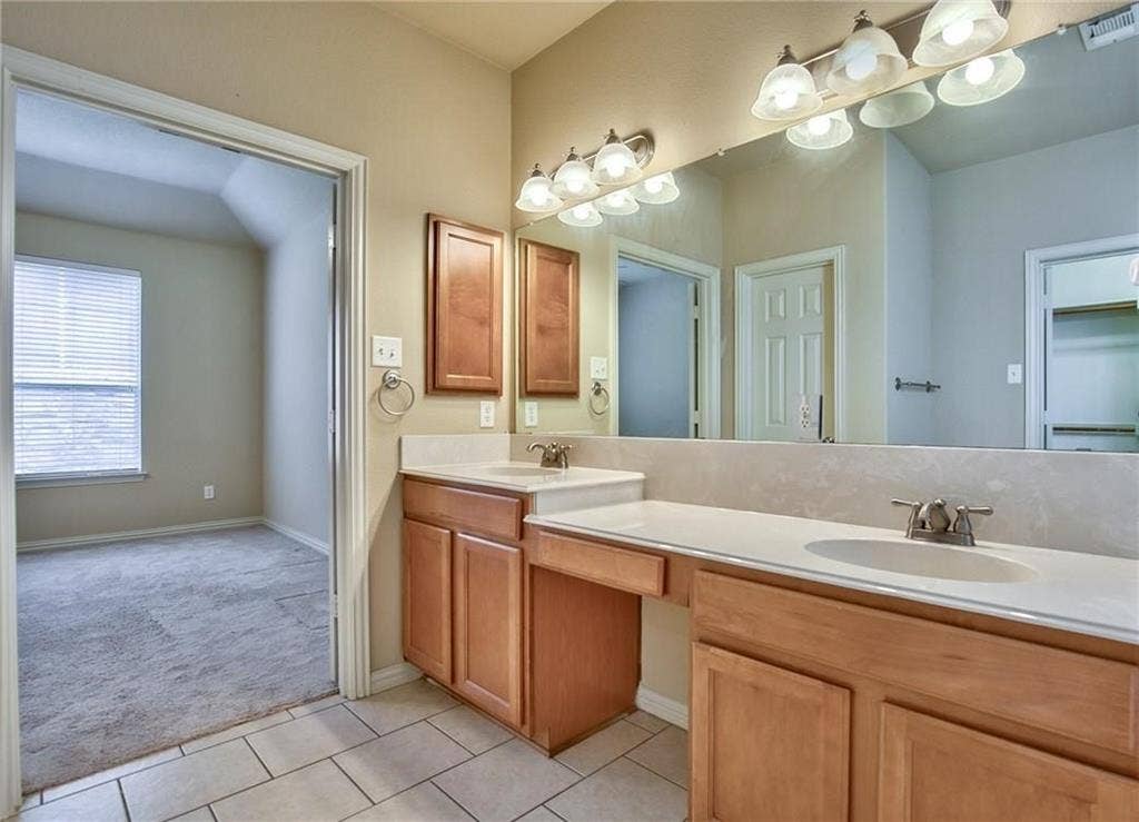 7108 Jessup Court, Plano, TX 75074 Double vanity with integrated sinks, ample countertop space, wood-finish cabinetry, and ceramic tile flooring