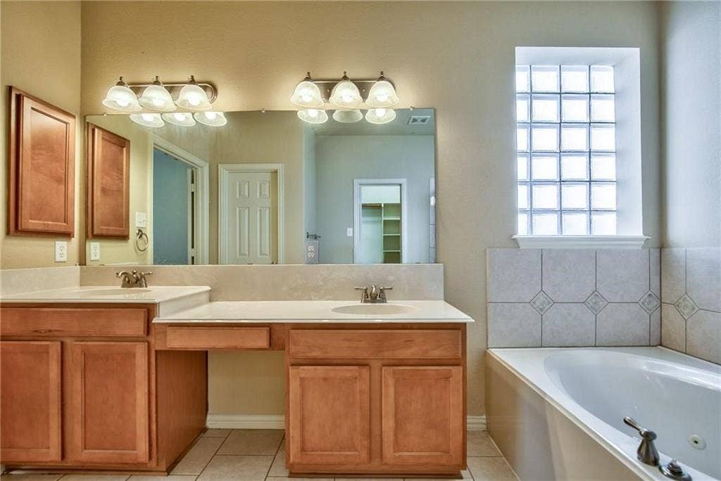 7108 Jessup Court, Plano, TX 75074 Dual wood-finish vanities with integrated sinks, a large wall-mounted mirror, and a built-in jetted tub