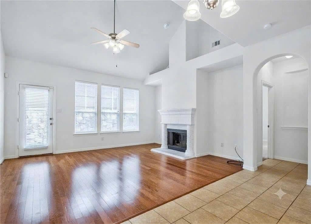 7108 Jessup Court, Plano, TX 75074 Vaulted ceilings, wood-finish flooring, fireplace with white mantel, multiple windows, and a ceiling fan