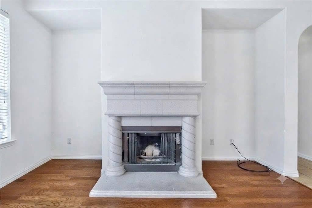 7108 Jessup Court, Plano, TX 75074 Fireplace with stone surround and hearth, fluted columns, and arched alcoves