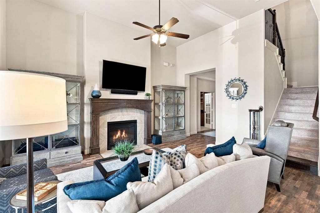 Vaulted ceilings, wood-finish flooring, fireplace with stone surround, and a staircase with wrought iron balusters