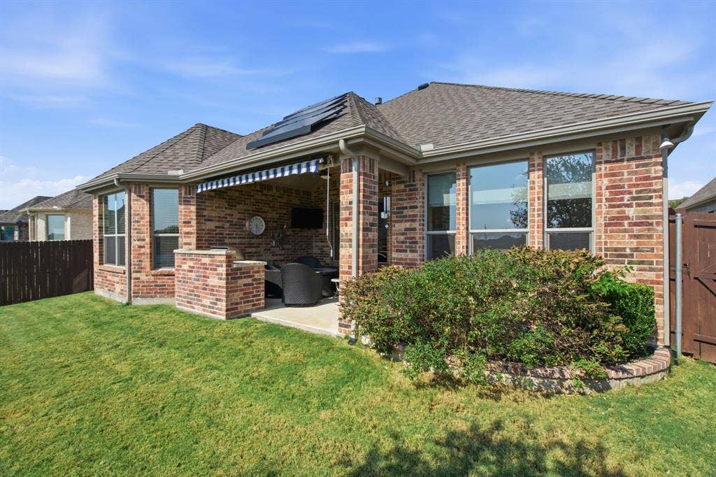 Brick exterior with a covered patio, built-in brick island, and a retractable awning