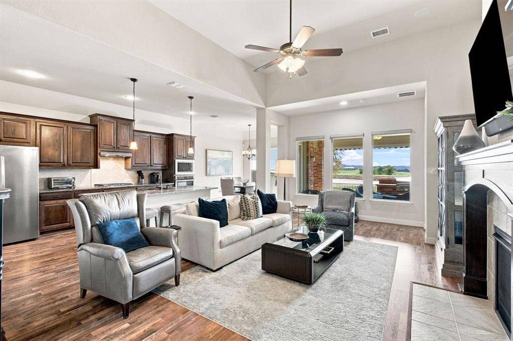 Vaulted ceiling with a ceiling fan, recessed lighting, wood-finish flooring, built-in fireplace, and a kitchen with wood cabinetry