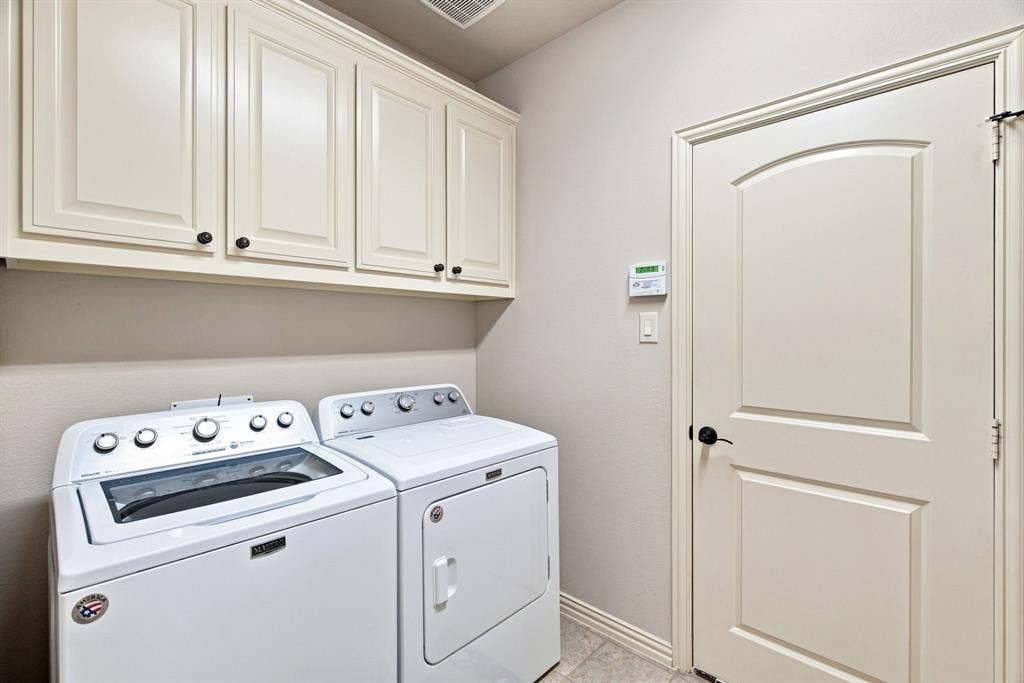 Utility room featuring built-in upper cabinetry, paneled door, and tile flooring