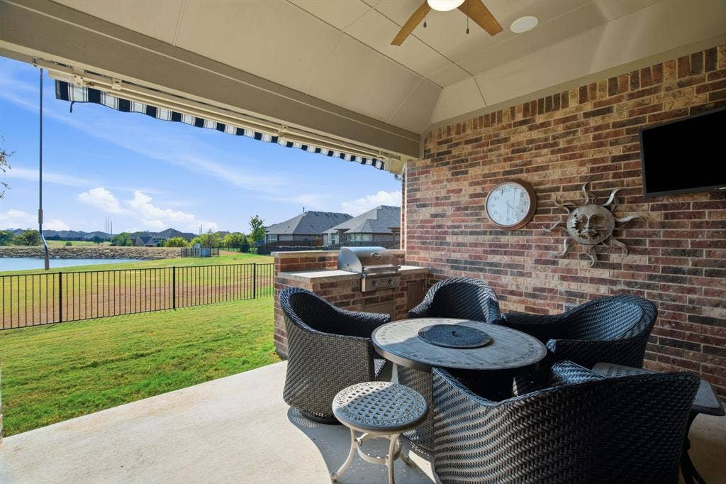 Backs up to Lake with covered patio, built-in grill, ceiling fan, and concrete floor.