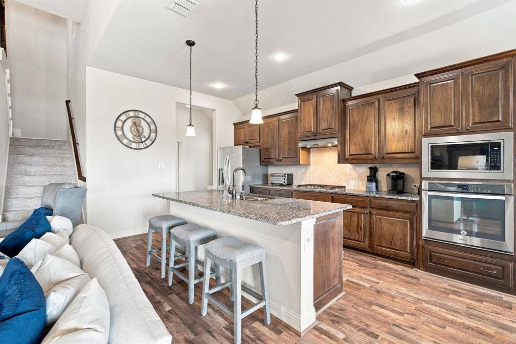 Kitchen featuring wood-finish flooring, dark wood cabinetry, stainless steel appliances, and a central island with a light-toned countertop