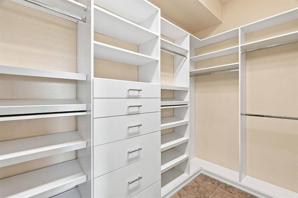 Custom closet system featuring multiple shelving units, built-in drawers with brushed nickel hardware, and ample hanging rods