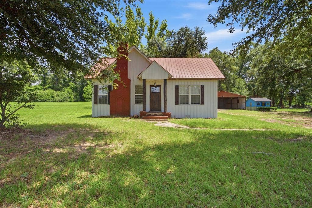 506 E Longview Street, Arp, TX 75750 White siding exterior with a red metal roof and red brick chimney
