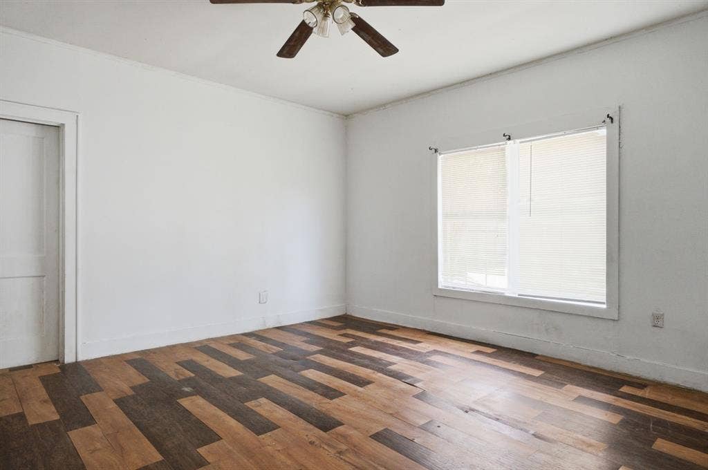 506 E Longview Street, Arp, TX 75750 Room featuring multi-tone wood-finish flooring, white walls, and a ceiling fan with light fixture