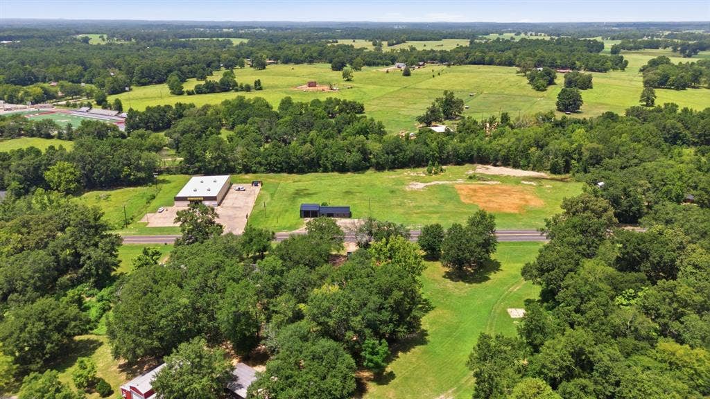 506 E Longview Street, Arp, TX 75750 Expansive property featuring a commercial building, a residential structure, and extensive green space